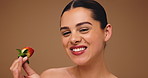 Beauty, health and strawberry with woman on wall background for diet, detox or nutrition. Cosmetics, face and wellness with happy model biting fruit on studio space for benefits of organic vitamins