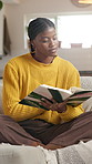 Black woman, reading book and relax on sofa, home and learning with novel, story or language in lounge. African person, student and literature for research project, education and info in living room