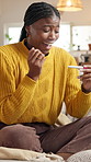 Surprise,  woman and pregnancy test results on sofa with fertility, IVF success and good news. Excited, black person and touch belly in house for pregnant confirmation, positive stick and gratitude