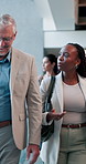 Smile, communication and walk with business people in convention center for conference, seminar or tradeshow. Man, discussion and chat with woman employee in lobby for event, expo or symposium