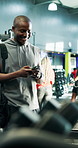 Smile, black man and phone for fitness at gym on social media, training schedule and membership. Male person, bodybuilder and barbell for weightlifting, mobile chat and workout challenge of endurance