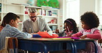 Conversation, man and students in classroom, learning and questions with child development. Group, teacher and kids in school, help and knowledge with growth, education and discussion with creativity