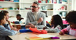 Man, teacher and children in classroom with discussion, anatomy and development with education at school. Mature person, kids and talk with guide, scholarship and show elbow for learning at academy
