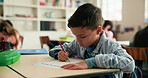 Learning, writing and child in classroom at school for test, assessment or project for education. Color pencil, student and boy kid with notebook for drawing with creative assignment at campus.