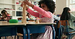 Learning, student and child with building blocks, classroom and creative game for fine motor skills. School, girl and pupil with cognitive development, knowledge or problem solving with wooden shapes
