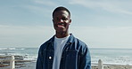 Face, smile and thinking with black man at beach for morning fresh air or inspiration outdoor. Future, idea and vision with African person on promenade at coast for break, relax or weekend wellness