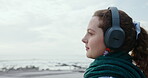 Woman, thoughts and headphones at beach for travel ideas, holiday vision and listening to music. Thinking, female person and space with fresh air, streaming podcast and reflection for ocean vacation