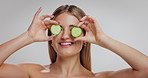 Woman, beauty and cucumber with face in studio, smile and mockup space with nutrition on white background. Girl, model and happy with organic fruit for detox, diet benefits and skincare in Germany