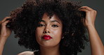 Portrait, haircare and afro woman with touch, volume and frizz control in styling product. Space, coil management or African lady with makeup, soft texture or natural shine on grey studio background