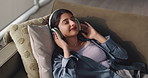 Woman, headphones and dance on sofa, relax and above in home with smile, streaming or eyes closed in lounge. Person, audio and listen to music on couch with subscription, song and happy at apartment