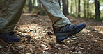 Person, hiking and legs with shoes in forest for outdoor adventure, journey or exploration. Hiker, trekking and walking with sneakers on path for travel, expedition or health in pine woods or nature