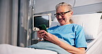 Healthcare, phone and smile of old woman in hospital bed for recovery from operation or surgery. App, social media and test message with happy senior patient in clinic for communication or treatment