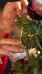 Christmas tree, decoration and hands of woman in home for festive celebration or tradition. Creative, holiday and party with person hanging ball in apartment for preparation of December season