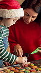 Cookies, support and Christmas with mother and daughter in kitchen for bonding, holiday season and help. Santa snack, sprinkles and festive dessert with woman and kid in family home for frosting
