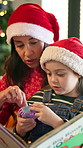 Christmas, toy and mother with child in home for playing together with bonding in living room. Story book, connection and mom with girl kid for xmas celebration in festive season at apartment.
