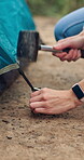 Hammer, hands and tent set up with person on campsite for adventure or sightseeing trip. Mallet, preparation and shelter with hiker outdoor in nature, getting ready for camping holiday or vacation