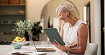 Tablet, laptop and mature woman in house with research for finance report with freelance career. Digital technology, computer and financial advisor with online budget planning in kitchen at home.