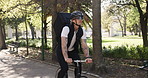 Man, bicycle and delivery with bag in park for travel, package or parcel transportation in nature. Male person, commute or outdoor ride with bike, helmet or backpack for eco friendly courier service