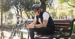 Man, delivery and bench with bicycle or phone for break, navigation app or route in park. Male person, courier guy and rest with bike, helmet or mobile smartphone for logistics or transport service