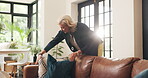 Mature woman, cleaning and sofa at house for tidy living room, interior comfort or home improvement. Female person, arrange and cushion for decoration, neat couch and furniture aesthetic of household