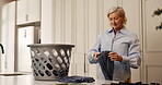 Mature woman, folding and laundry at house for hygiene, clean clothes and housekeeping routine. Female person, basket and fresh apparel of household chores, organizing washing and maintenance service
