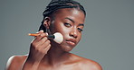 Face, brush and black woman in studio, makeup and foundation on gray background. Space, cosmetic tools and African person with shine, confidence and dermatology with glow, beauty and aesthetic