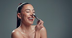 Smile, brush and woman in studio, makeup and wellness with beauty, pride and aesthetic. Space, cosmetics tool and person with confidence, funny and facial treatment with skincare on grey background