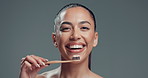 Dental health, toothbrush and face of woman in studio with routine for fresh breath. Happy, toothpaste and portrait of female person brushing teeth for oral care and hygiene by gray background.