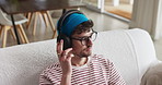 Headphones, relax and man on sofa in house with listening to music, playlist or radio on weekend. Happy, audio tech and male person streaming album, podcast or song online in living room at apartment