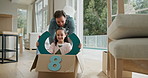 Father, child or driving in box in new home for property investment, mortgage security or race game. Family house, excited people and push with fantasy steering wheel for relocation fun and bonding