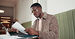 Reading, paperwork and black man with laptop in coffee shop, research and learning for scholarship. Education, glasses and college student with pc for studying, test review and class notes in cafe.