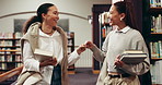 Woman, college student and friends at library with fist bump, greeting and happy at academy. Girl, reunion and hello with books, education and discussion for learning with scholarship at university