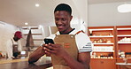 Happy man, waiter or typing in cafe with phone for communication, text message or online chat. Smile, black person or employee in restaurant with tech for internet search, social media or mobile app.