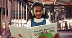 Reading, book and child with headphones, library and learning with fiction, surprised and happiness. Shocked, girl and growth with literature, education and kid with noise canceling tech in school