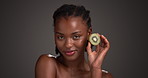 Kiwi, skincare and smell with face of black woman in studio for beauty, vitamin c and organic glow. Natural dermatology, space and cosmetics with person and fruit n dark background for fragrance