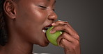 Black woman, diet and mouth with apple in studio for health or beauty on a gray background. Female person, African model or bite with natural organic green fruit for antioxidant or vitamin on space