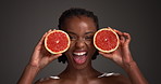 Grapefruit, skincare and face of black woman in studio for vitamin c, beauty and natural cosmetics. Exfoliating enzyme, facial glow and dermatology with person and fruit on dark background for detox