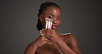 Face, African woman and makeup with brushes in studio, blush powder and natural for skin glow. Facial color, calm person and cosmetics tools for results, space and beauty aesthetic on gray background