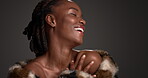 Skincare, smile and black woman in studio with coat, designer or luxury cosmetics in body product. Face, glow or female person on gray background with confidence, glamour or trendy in modern beauty.