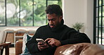 Frown, phone and scam with man on sofa in living room of home for social media or text message. Confused, doubt and typing with unhappy person in apartment for communication, mobile fraud or phishing