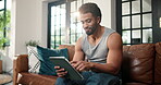 Smile, typing and tablet with man on sofa for streaming service notification and reading. Movie subscription search, online film and media app with person in living room of home for download