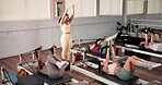 Fitness, pilates reformer and women with personal trainer in gym for demonstration or routine. Challenge, exercise and machine with instructor teaching student group in health club for performance