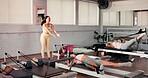 Exercise, pilates reformer and women with personal trainer in gym for demonstration or routine. Challenge, fitness and machine with instructor teaching student group in health club for performance