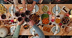 Above, hands and toast with people at dining room table together for thanksgiving celebration. Food, holiday cheers and social gathering with friends drinking red wine in home for dinner or event