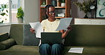 Black woman, remote work and laptop with paperwork on couch for information, internet and online. Female freelancer, technology and document for fact comparison, connection and reading in home