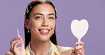 Face, mirror and woman with lip gloss, smile for beauty or apply makeup in studio. Girl, lipstick shine or liquid color in portrait with cosmetic product, happiness and glow on purple background