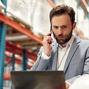 Phone call, shipping and man in warehouse with laptop, talking or ...