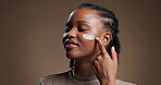 Skincare, cream and smile with black woman in studio for beauty, self care and cosmetics. Dermatology, mockup space and shine with person  on brown background for aesthetic, lotion and collagen
