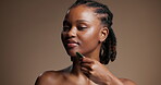 Black woman, massage and guasha for skincare in studio with beauty, facial detox and circulation. Person, cosmetic and tools for lymphatic drainage, dermatology and natural shine on brown background