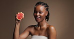 Skincare, woman face and squeeze grapefruit in studio, vitamin c and natural beauty for wellness. Portrait, happy person and dermatology with citrus fruit, skin glow and space on brown background.